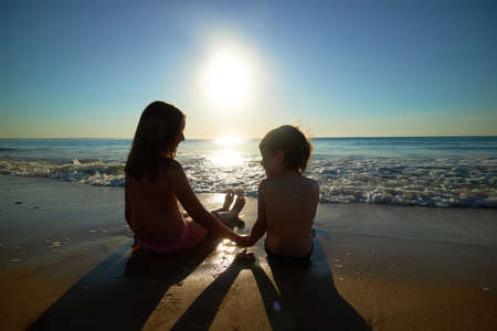 boy and girl on the sea at sunsetの写真素材