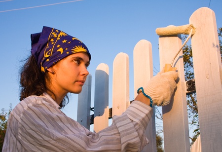 Beautiful girl colours the wooden fenceの写真素材