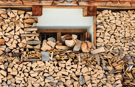 Firewood stacked in a woodpile near the wall of houseの写真素材