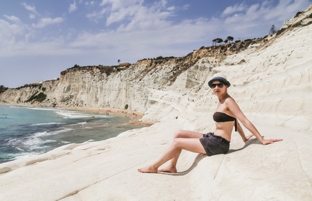 A girl sits on a slope of white cliff called "Scala dei Turchi" in Sicily, near Agrigento. Italyのeditorial素材