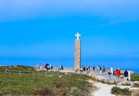 Ordinary tourists walk near Cross on Cabo da Roca, the most western point of European continentのeditorial素材