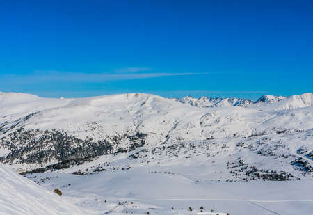 Beautiful mountain range covered in snow with clear sky on sunny day. Ski infrastructure and slopes in Pyrenees, Andorraの写真素材