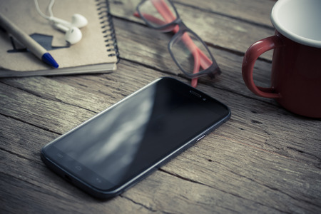Wood desk with smartphone, top viewの写真素材