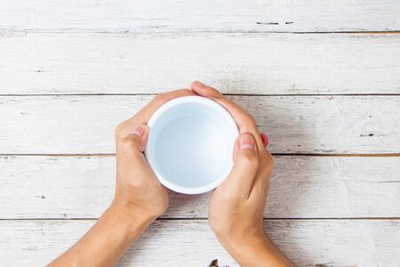 Top view hands holding in cup on wood backgroundの写真素材
