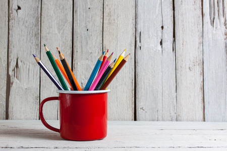 Stack of colored pencils in a glass on wooden backgroundの写真素材