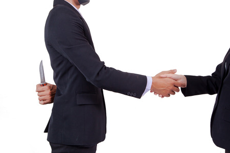 Stab back,two business men making a deal but hiding knivesの写真素材