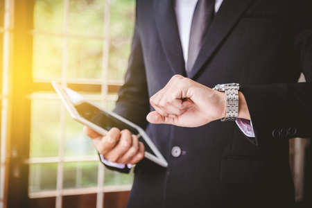 Businessman looking at his watch in officeの写真素材