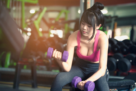 Young woman training with dumbbell in gymの写真素材