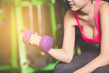 Young woman training with dumbbell in gymの写真素材