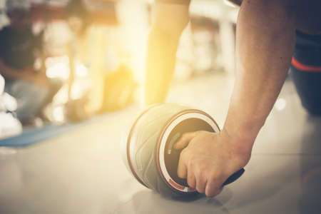 Man using abdominal roller for working out abdominals. Front view. Focus on hands.