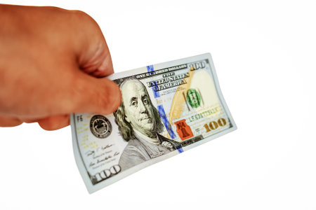 Man's hand holding a hundred dollar bill isolated on white background.の写真素材