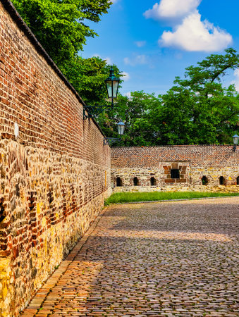 Historic Embrasures: Glimpse of a Medieval Fortress Wall â Captivating Brick Structure with Openings for Defense, Surrounded by Lush Greenery and Beautiful Blue Skyの写真素材