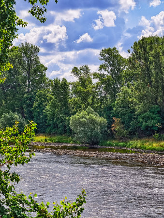 Scenic Riverbank with Lush Green Trees and Fluffy Clouds â€“ Breathtaking Abstract Background...