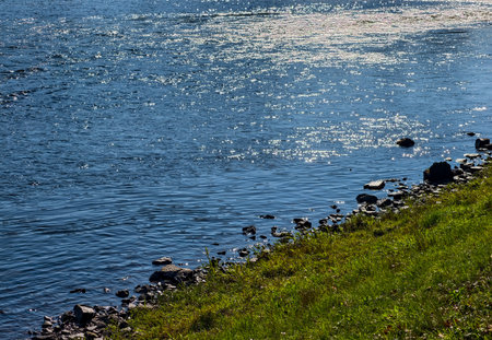 Lakeside Landscape with Sparkling Blue Water, Green Grass and Rocks - Nature Wallpaper. Ultra High...