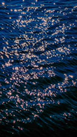 Golden Sunlight Sparkle on Dark Blue Ocean Water Surface - 8K Ultra High-Resolution Vertical Wallpaper Background with Copy Space for Luxury and Travel Design.の写真素材