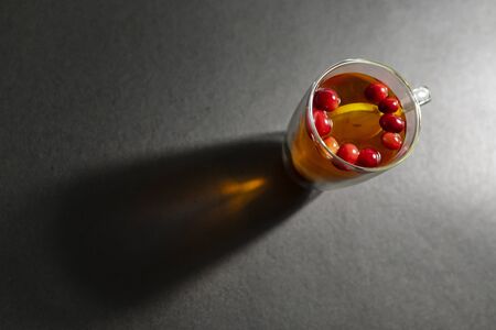 Winter drink with black tea, with whole cranberry berries laid out in a semicircle, with a whole...