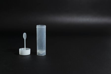 Open sterile white plastic container or jar for stool analysis or coprological test on a black background. Lid and container separately. Horizontal close-up.の写真素材
