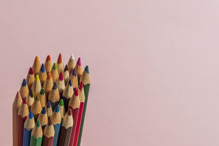 Multi-colored pencils located on the left side on a pink background. Horizontal close-up.の写真素材