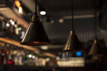 Metallic dark retro chandeliers are suspended from the ceiling. Modern, relevant and at the same time vintage design. Conceptual style. Loft lamps hang in a restaurant or cafe, in a bar or club, in art or loft space. Ideal for modern decor. The foreground is clear, in focus. The background is out of focus, blurred. Horizontal view.の写真素材