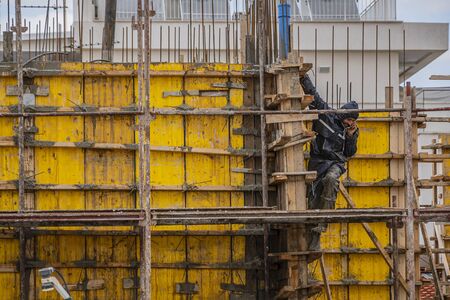A man in a special working dirty blue uniform talks on the phone and goes down the stairs. A builder...