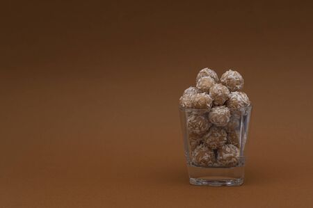 Raw and healthy energy balls in coconut in transparent glass on a brown background. Horizontal view. Side view. Copy spaceの写真素材