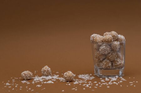 Organic healthy snacks in coconut flakes in a transparent glass cup. Three energy balls and coconut...