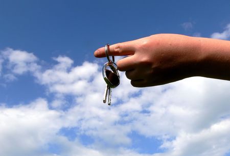 Hand and keys on blue sky with cloudsの写真素材