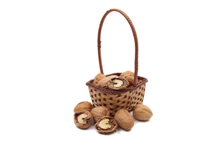 Walnuts in wicker basket isolated on white backgroundの写真素材