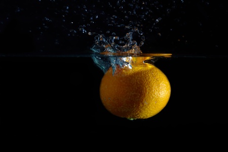 Orange and splash water over black backgroundの写真素材