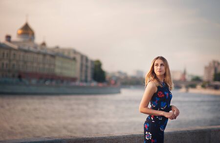 Beautiful blonde sexy tourist girl walking in busy city street with long hair flying on the wind. Woman looking at camera outdoors wearing fashionable white t-shirt. Moscow lifestyle photo.の写真素材