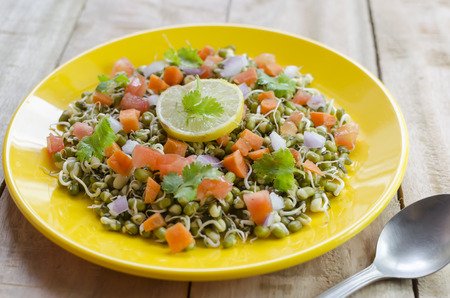 Sprout salad made with green gram sprouts,carrots,tomatoes,onions and lime juiceの写真素材