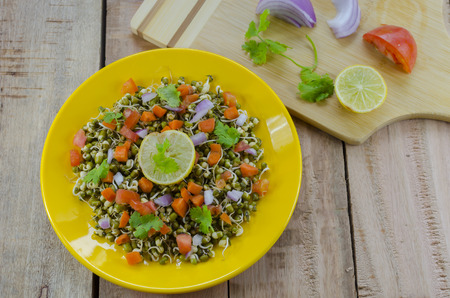 Sprout salad made with green gram sprouts,carrots,tomatoes,onions and lime juiceの写真素材