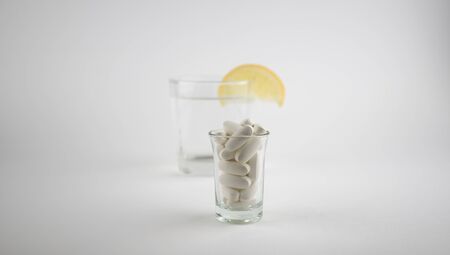 Glass with pills isolated on grey background