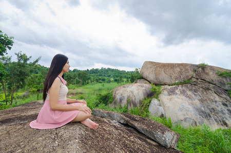 Woman Yoga meditation sitting on stones with mountains and blue sky on background harmony with nature concept.の写真素材
