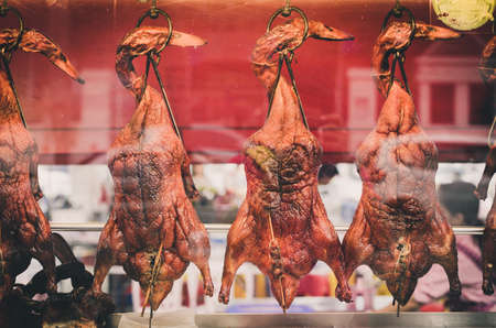 Roasted ducks hanging in restaurant window.の写真素材