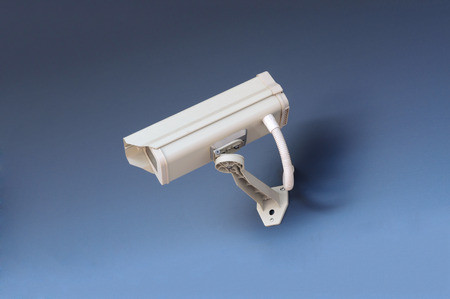 Security CCTV camera in office building on blue background.