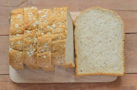 Whole wheat bread cut on sliced loaf rye bread on a wooden board.