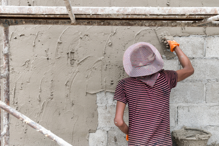 Close up of industrial bricklayer installing cement on construction siteの写真素材