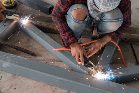 Worker while doing a welding with arc welder.