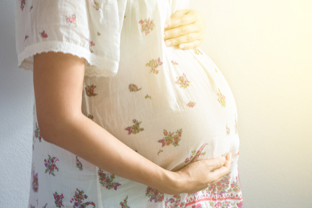 Image closeup of pregnant woman touching her belly with hands.の写真素材