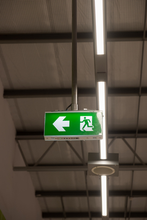 Fire exit light sign. Green emergency exit sign showing the way to escape.の写真素材