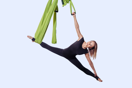 Young woman doing aerial yoga in green hammock.の写真素材