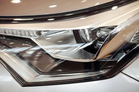 Closeup of a car headlight. Headlight of an expensive new car at a car dealershipの写真素材