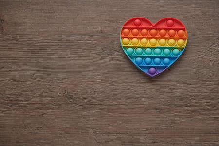 Heart, silicone colorful anti-stress pop it toy on wooden background. Click the pop up bubble. simple toy with dimples, close-up. The concept of romance, love, gift, valentine's day, holidayの写真素材