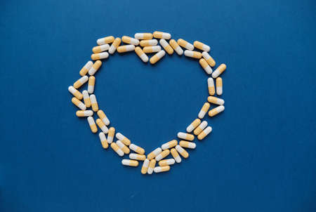Symbolic contour of heart from yellow white capsules. Health, super food concept, vitamins,...