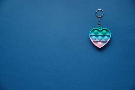 Keychain Heart, silicone colorful anti-stress toy on blue background. Click pop up bubble. A simple...
