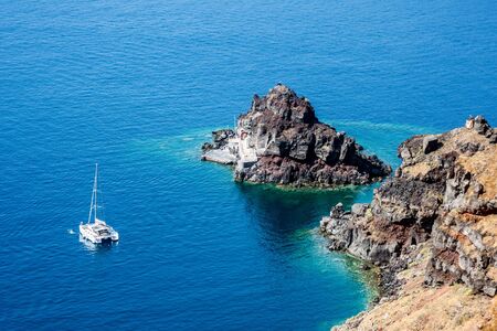A catamaran anchored off the coast of Santorini, Greece.の写真素材