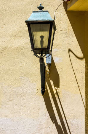 A lamp in an Athens strret casts shadows on a wall in brigjht sunlight.の写真素材