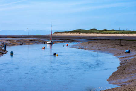 A yacht lies at anchor on the remote and muddy beach at Hightown.の写真素材