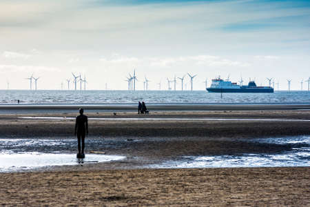 A ferry sails into Liverpool while an Antony Gormley statue looks on.の写真素材